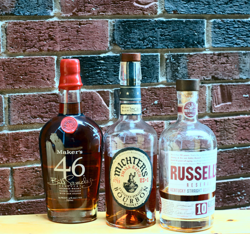 bottles of Makers 46, Michter's Bourbon, and Russells's Reserve. Three bourbons everyone should have
