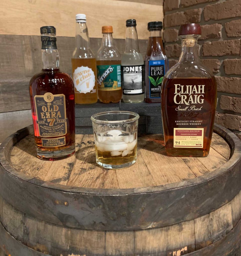 Bottles of mixers with a bottle of Old Ezra 7 and Elijah Craig Bourbon